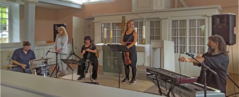 Weltmusik aus Chile in der Kirche Eichenberg. Barbara Freeman (hell gekleidet) vom Gemeindevorstand begrüßt das SUBHIRA-Quartett. Von rechts: SUBHIRA Rodrigo Cepeda, Petra Onderuf, Javier Cienfuegos, Pau Zañartu